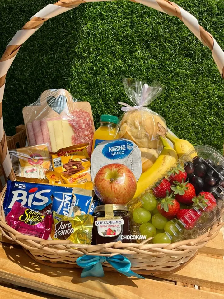 Cesta de café da manhã com frutas, pães, chocolates e bebida